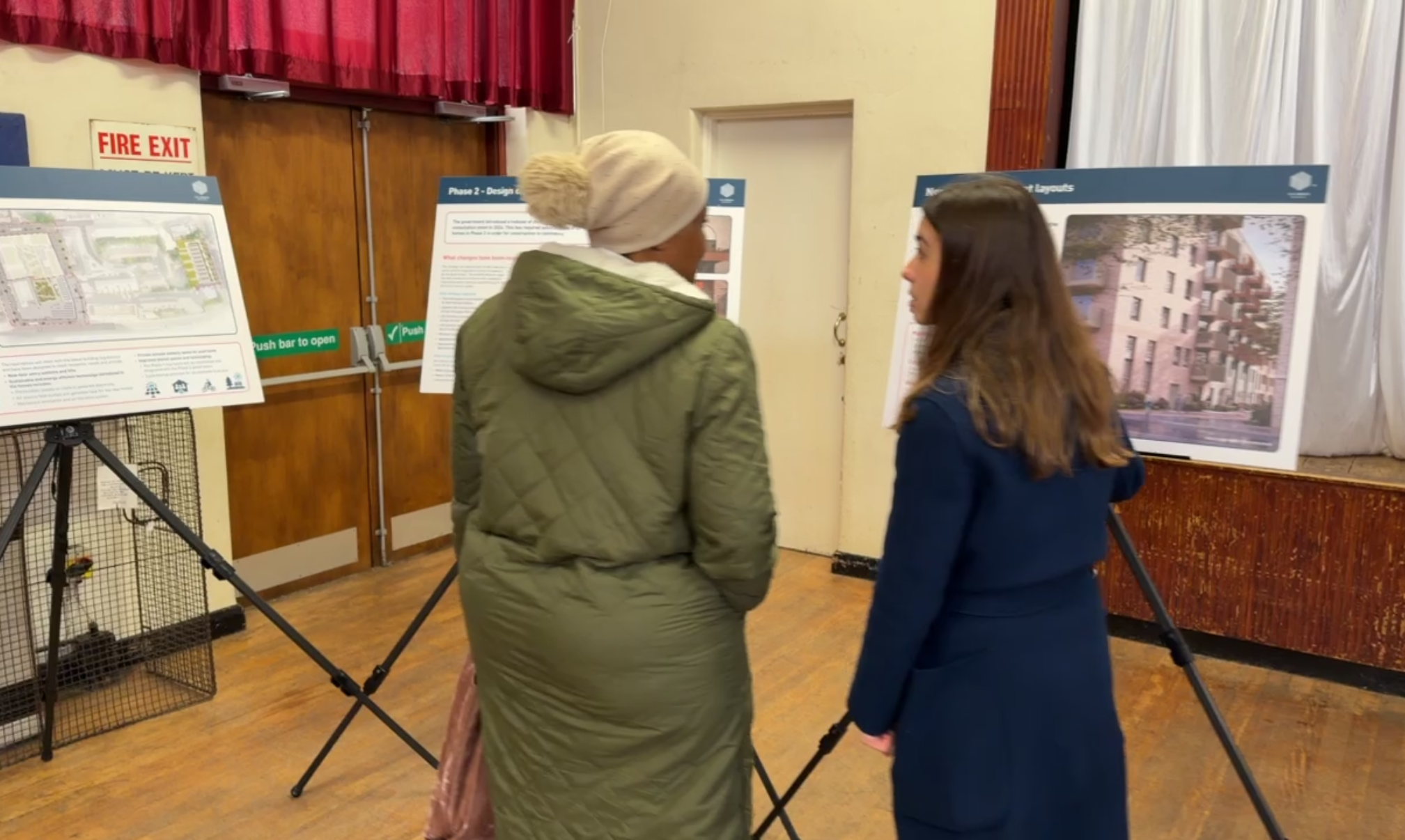 Two residents viewing exhibition boards at a Clare House redevelopment consultation event.